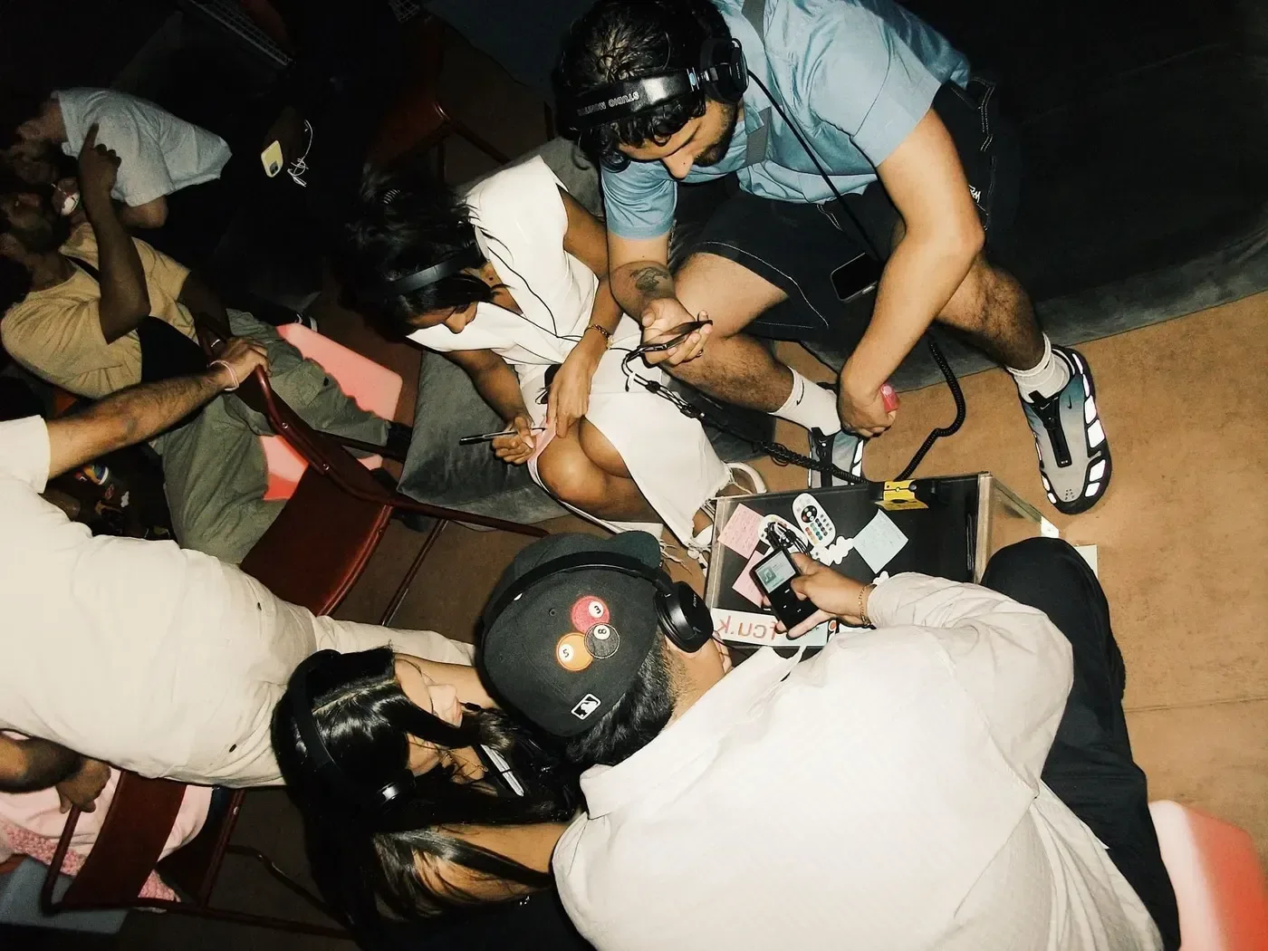H.LLS fans at a listening session, headphones on, phones and a recorder in hand