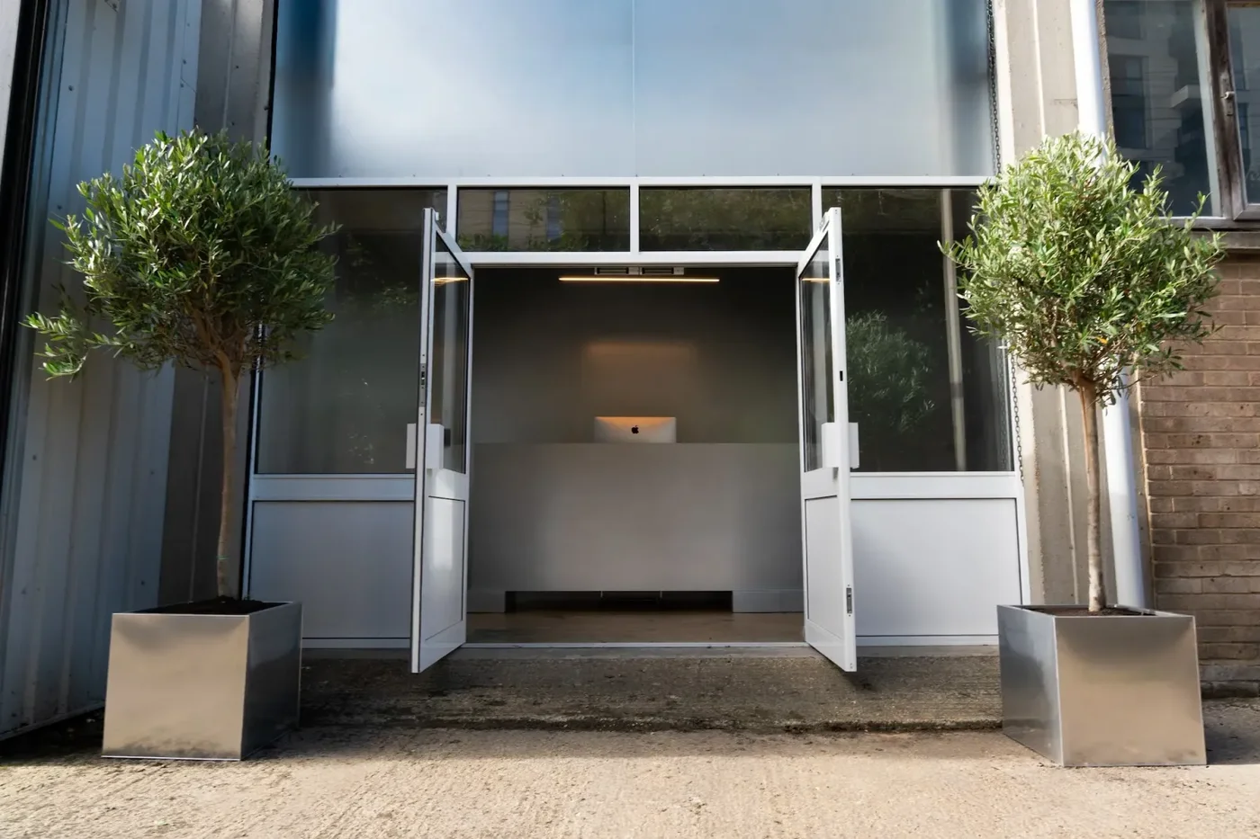 The YOU Studio entrance: open double doors between two olive trees